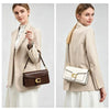 A woman models a beige blazer and white skirt, holding a brown leather shoulder bag.