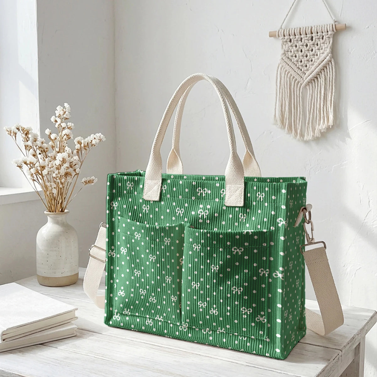 Sac en velours côtelé vert à pois blancs sur une surface en bois blanc avec des fleurs séchées.