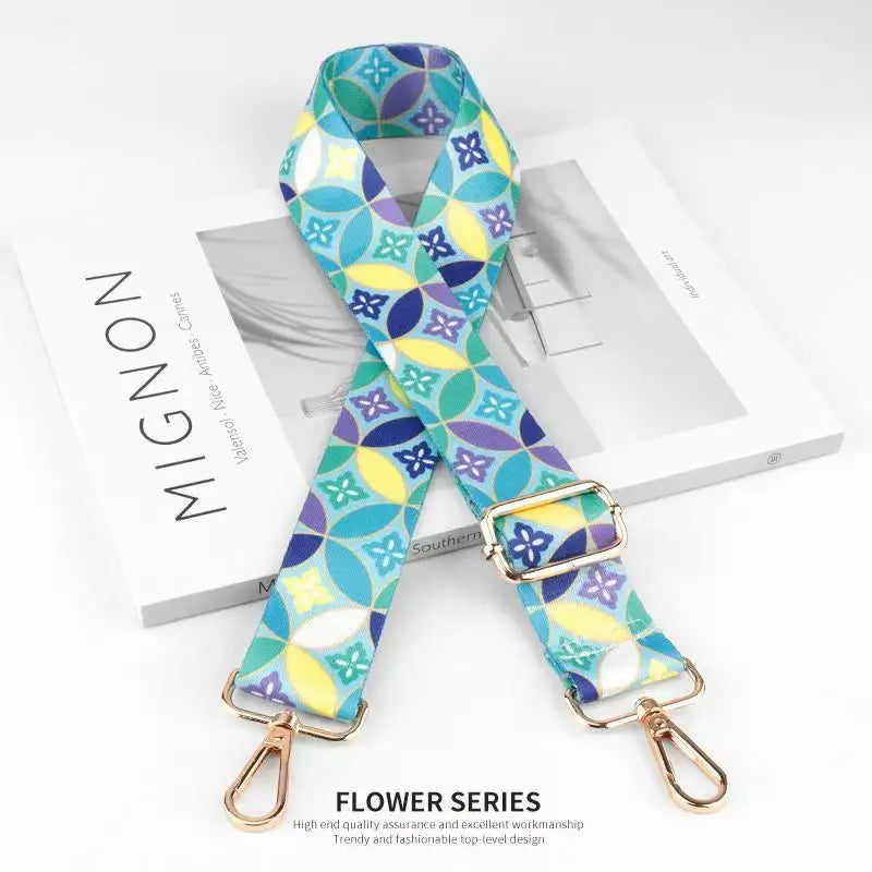 A colorful patterned nylon bag strap featuring blue, yellow, and green floral designs.