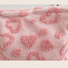 A pink, fluffy storage bag with a heart pattern for cosmetics and travel.