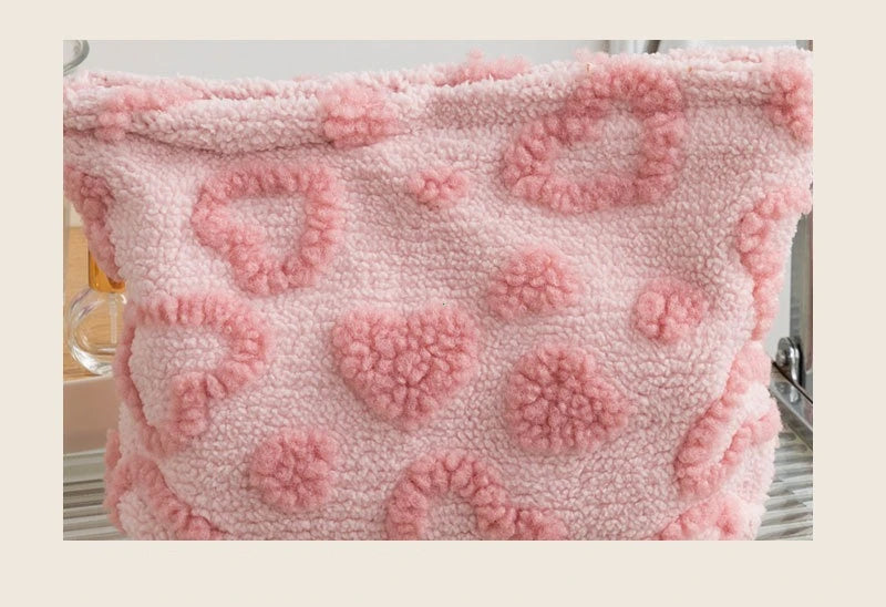 A pink, fluffy storage bag with a heart pattern for cosmetics and travel.