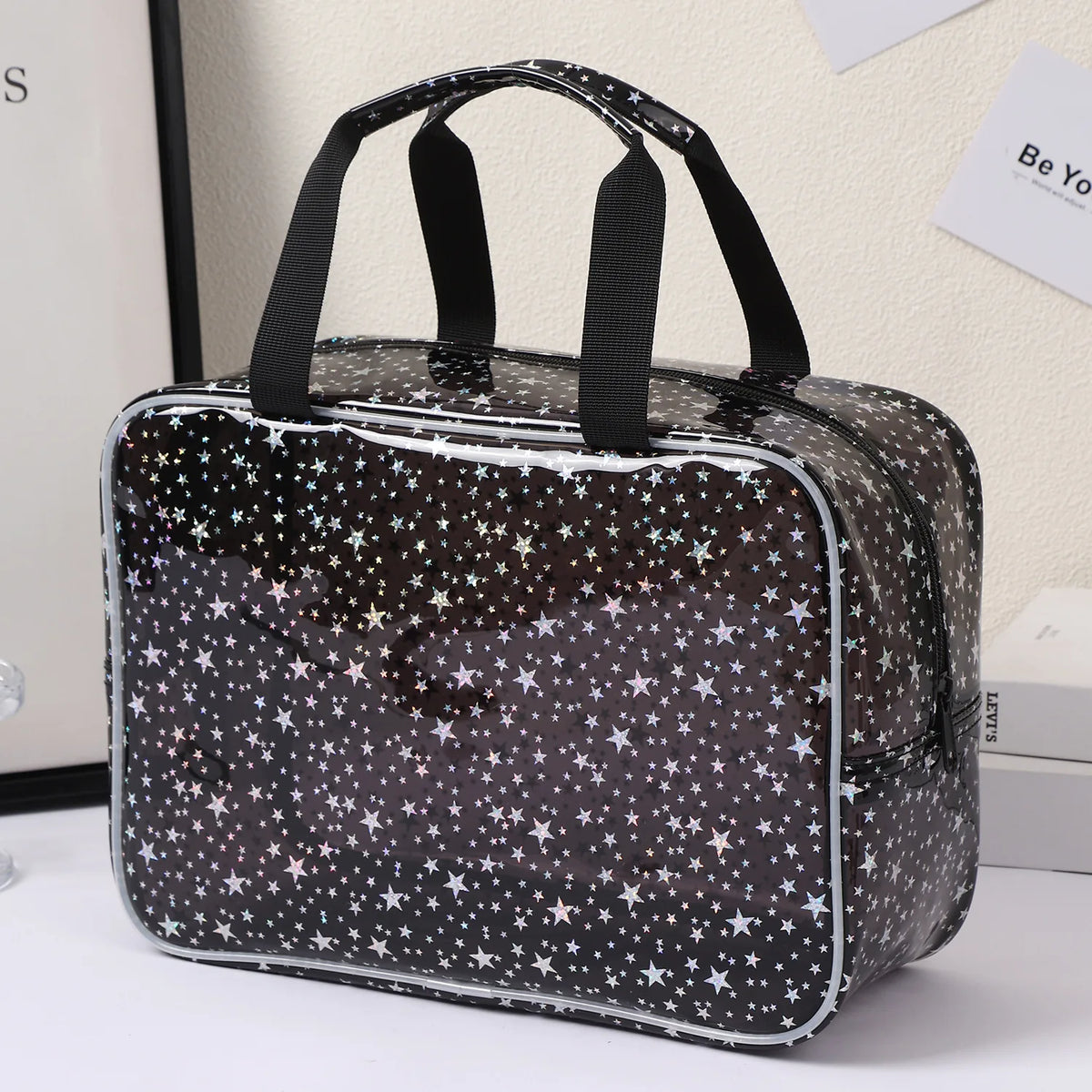A clear waterproof makeup organizer bag with a black and white star pattern sits on a white surface.