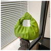 Un bolso de mano con lazo brillante verde lima y purpurina, mostrado contra una persiana blanca.