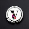Silver foldable letter hanger hook with a floral design on a black background