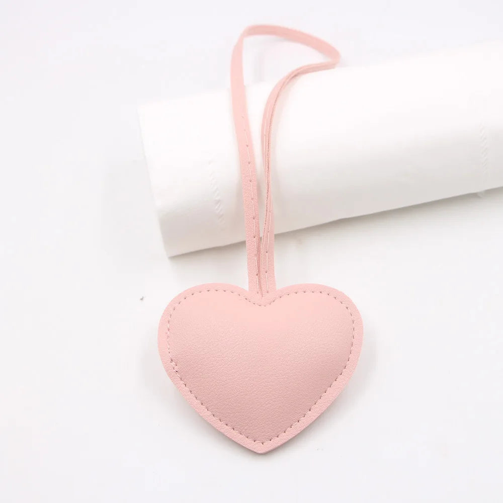 A pink PU leather heart-shaped keychain attached to a white rolled cloth.