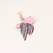 A pink and black patterned silk ribbon bow keychain with a gold-colored loop.