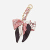 A pink and black patterned fabric strap with a gold-colored metal clip for an adjustable bag strap.