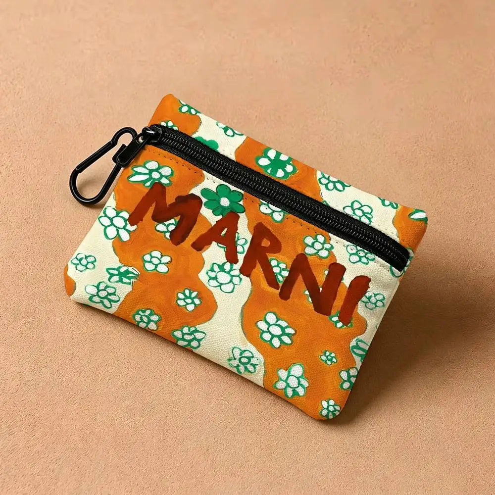 An orange and white floral print mini coin purse with a black carabiner clip.