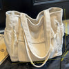 Sac fourre-tout en velours côtelé crème avec rainures verticales et plusieurs poches, présenté sur fond sombre.