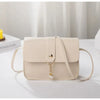 A beige fashion square crossbody bag with gold hardware resting on a white surface.