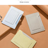 Trois porte-cartes ou portefeuilles de voyage fins de couleur claire sur une surface beige.