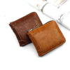 A brown vintage PU leather zipper card wallet resting on a white surface next to a rolled document.