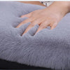A hand rests on a soft gray plush car armrest cushion set.