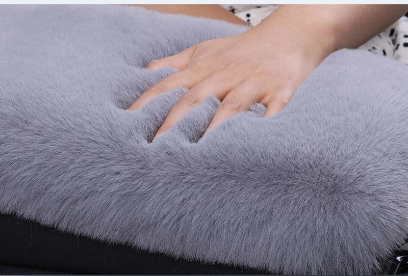A hand rests on a soft gray plush car armrest cushion set.