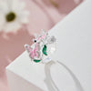 Silver butterfly rings featuring pink and green enamel flowers displayed on a white surface.