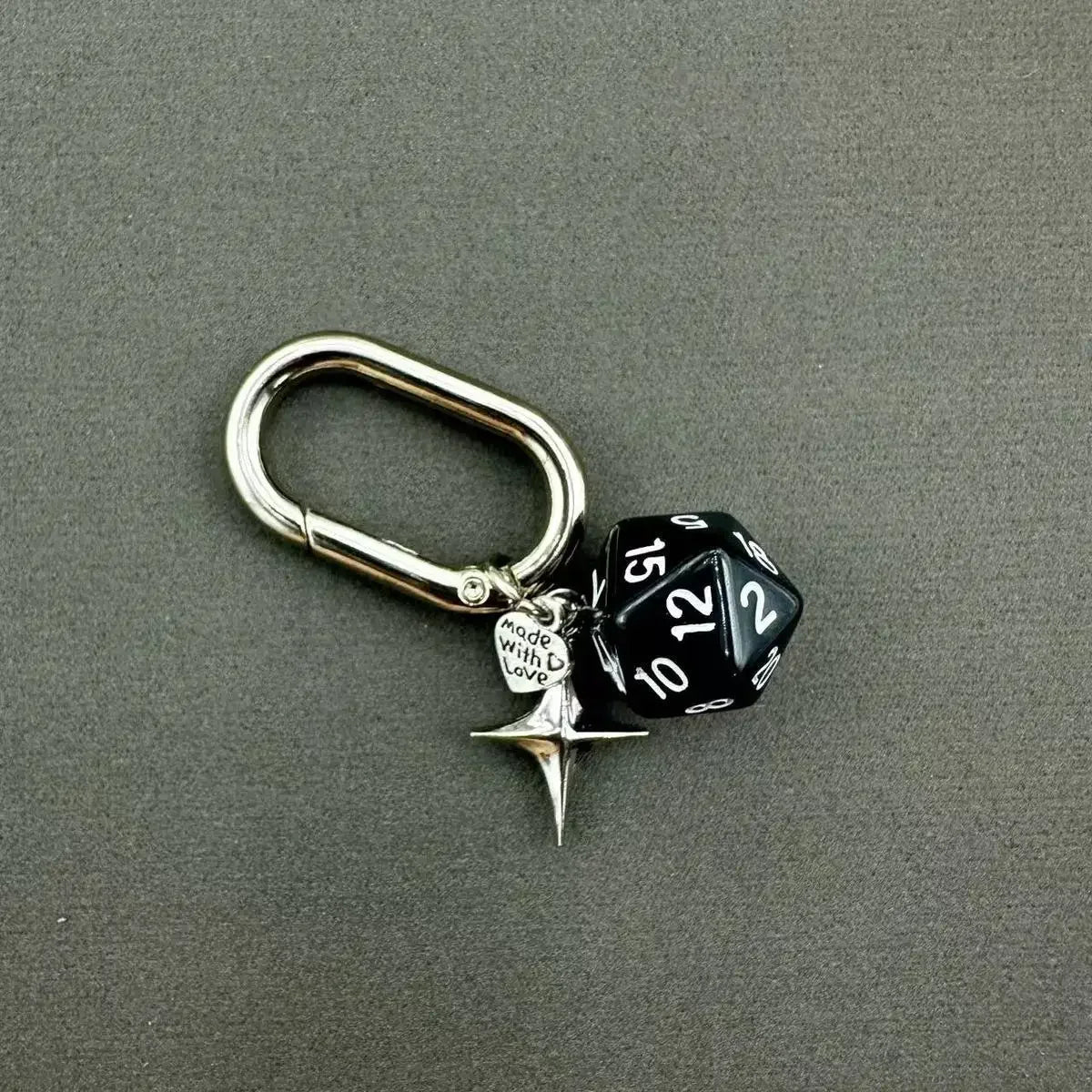 A silver-toned keychain featuring a black and white dice charm with a star pendant.