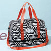 An orange nylon travel duffle bag with a black and white zebra stripe pattern.