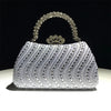 A silver crystal-embellished evening clutch bag with a crown-shaped clasp and chain strap, resting on a white surface.