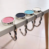 A row of metal desk hooks with glitter-filled containers for hanging bags and garments.