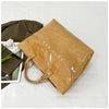 A tan transparent waterproof PVC tote bag is shown next to a dark olive green fabric item and a white flower.