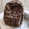 A brown and black leopard print plush backpack with multiple pockets shown on a white surface.