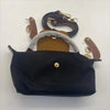 A black waterproof nylon crossbody bag with a tan leather strap and a detachable mini pouch.