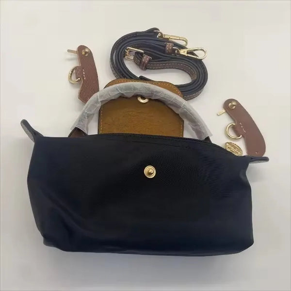 A black waterproof nylon crossbody bag with a tan leather strap and a detachable mini pouch.
