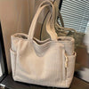 A beige casual corduroy handbag with vertical ribbing is displayed in front of a window blind.