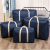 Navy blue foldable waterproof storage bags with tan straps displayed on a wooden floor.
