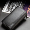 A black leather business handbag clip wallet displayed on a dark surface next to some magazines.