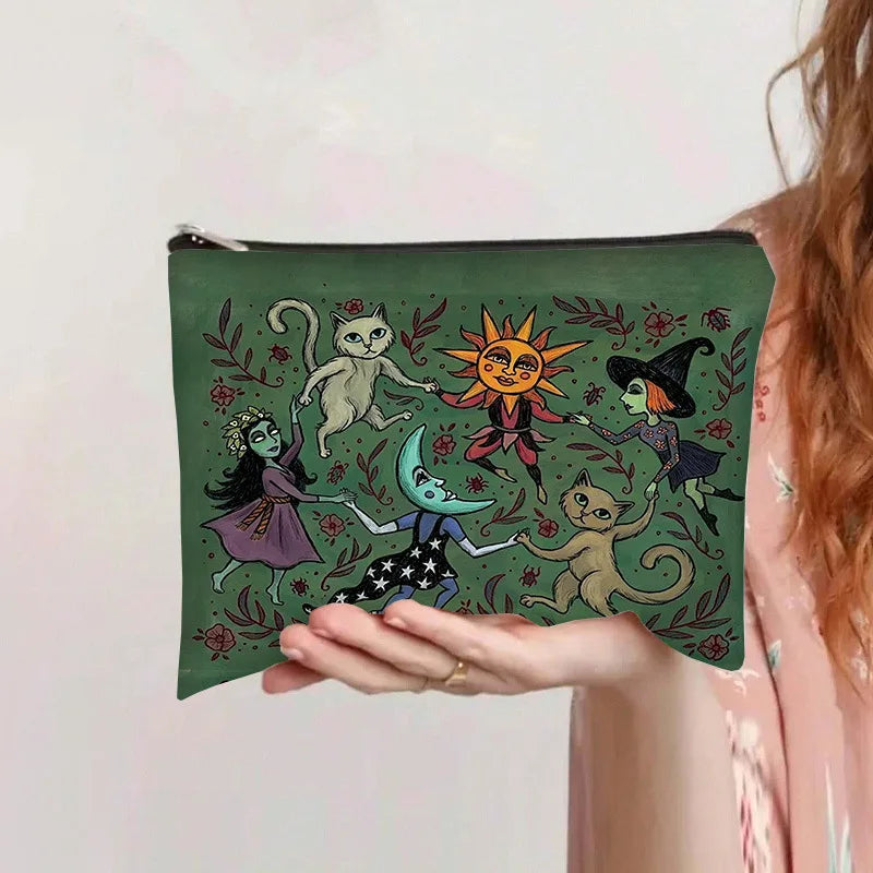 Una mano sostiene una bolsa de almacenamiento de cosméticos verde oscuro con ilustraciones caprichosas de gatos y un sol.
