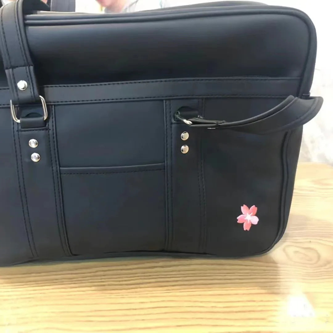 A black women's Japanese style PU shoulder bag with multiple compartments and a pink flower detail.