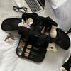 Schwarze, luxuriöse portable Make-up-Organizer-Tasche, geöffnet auf weißer Fläche mit verschiedenen Pinsel- und Produkten