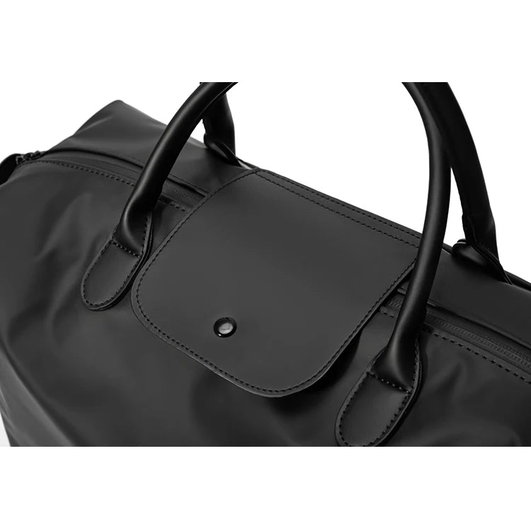 A close-up view of a black durable nylon travel duffle bag with leather handles.