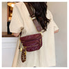 A woman is wearing a maroon Rivet waist bag crossbody fanny pack with gold hardware under a light beige jacket.