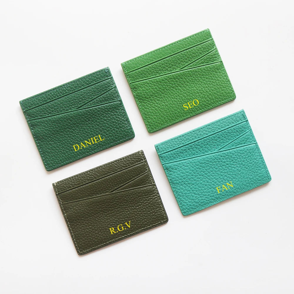 Trois porte-cartes en cuir vert gravés avec les noms et initiales : Daniel, R.G.V., et Fan.