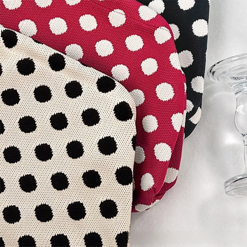 A close-up of a fabric featuring red and white polka dots, displayed next to a clear glass.