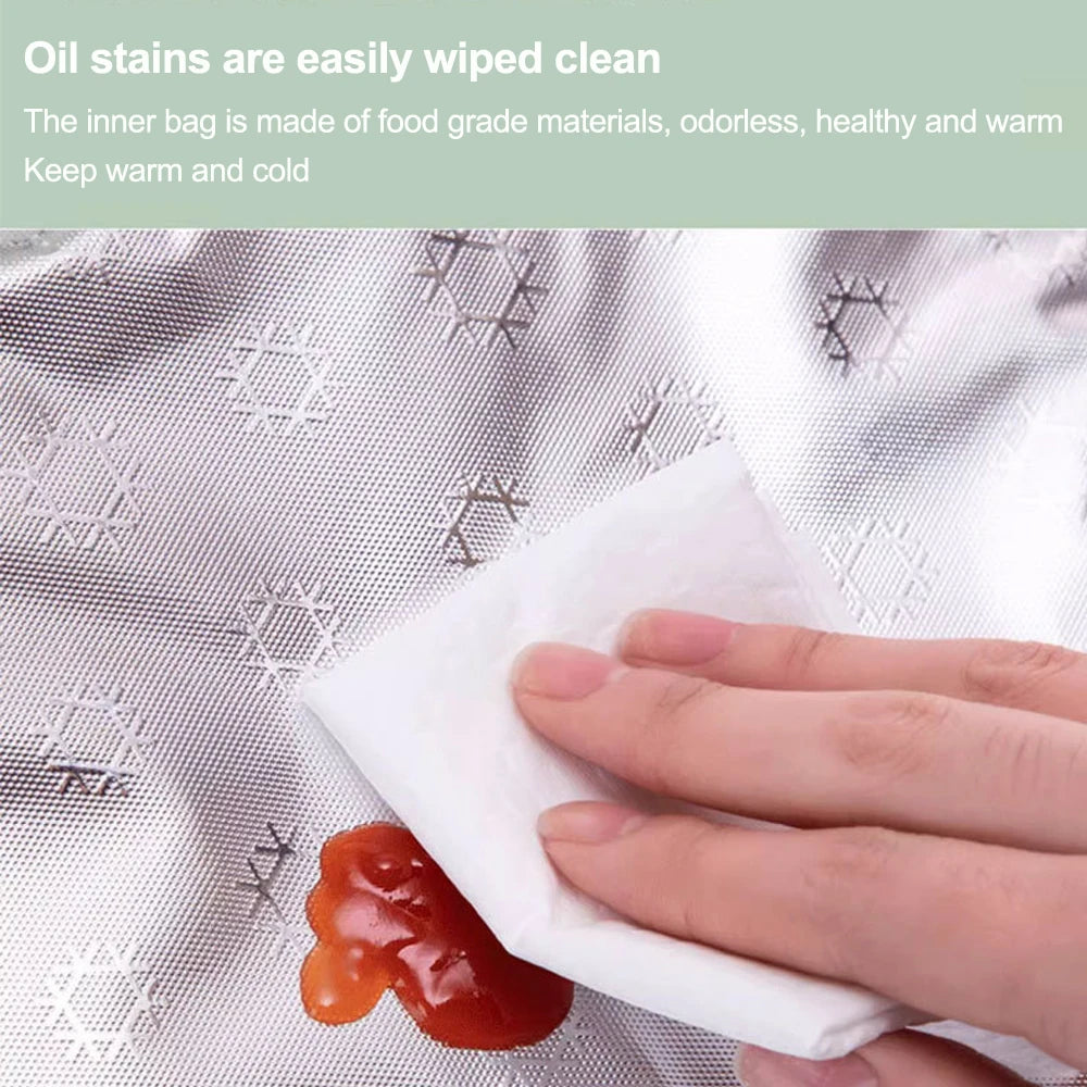 A hand wipes an oil stain off a white paper towel on a silver-patterned fabric.