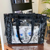 A black transparent shoulder tote bag with black leather straps and decorative elements.