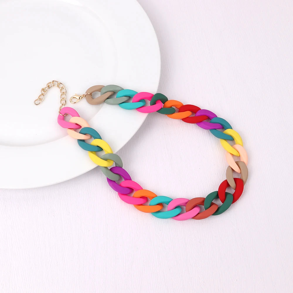 A colorful, multi-strand acrylic statement choker necklace with a gold-tone clasp resting on a white plate.