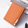 A rectangular orange faux leather business card wallet resting on a white surface next to a book.