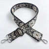 A black and beige patterned jacquard strap for a crossbody bag, shown crossed.