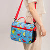 Una bolsa de almuerzo aislada de color azul brillante con una correa roja es llevada por una persona.