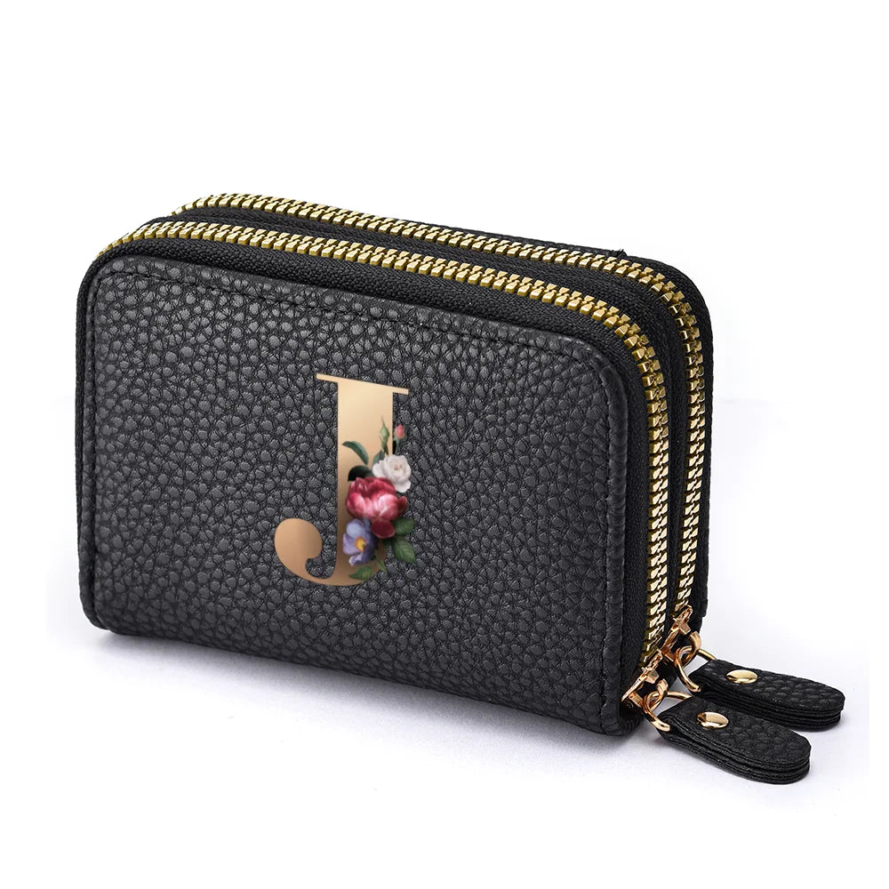 Black faux leather mini wallet with a gold letter J and floral print, featuring a double zipper.