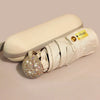 A compact white rhinestone umbrella with a gold-colored UV protection tag is shown lying on a light surface.