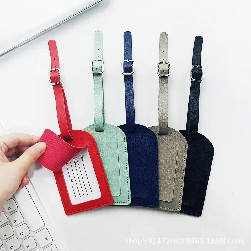 Five colored PU leather luggage tags with names and addresses are displayed on a white surface.