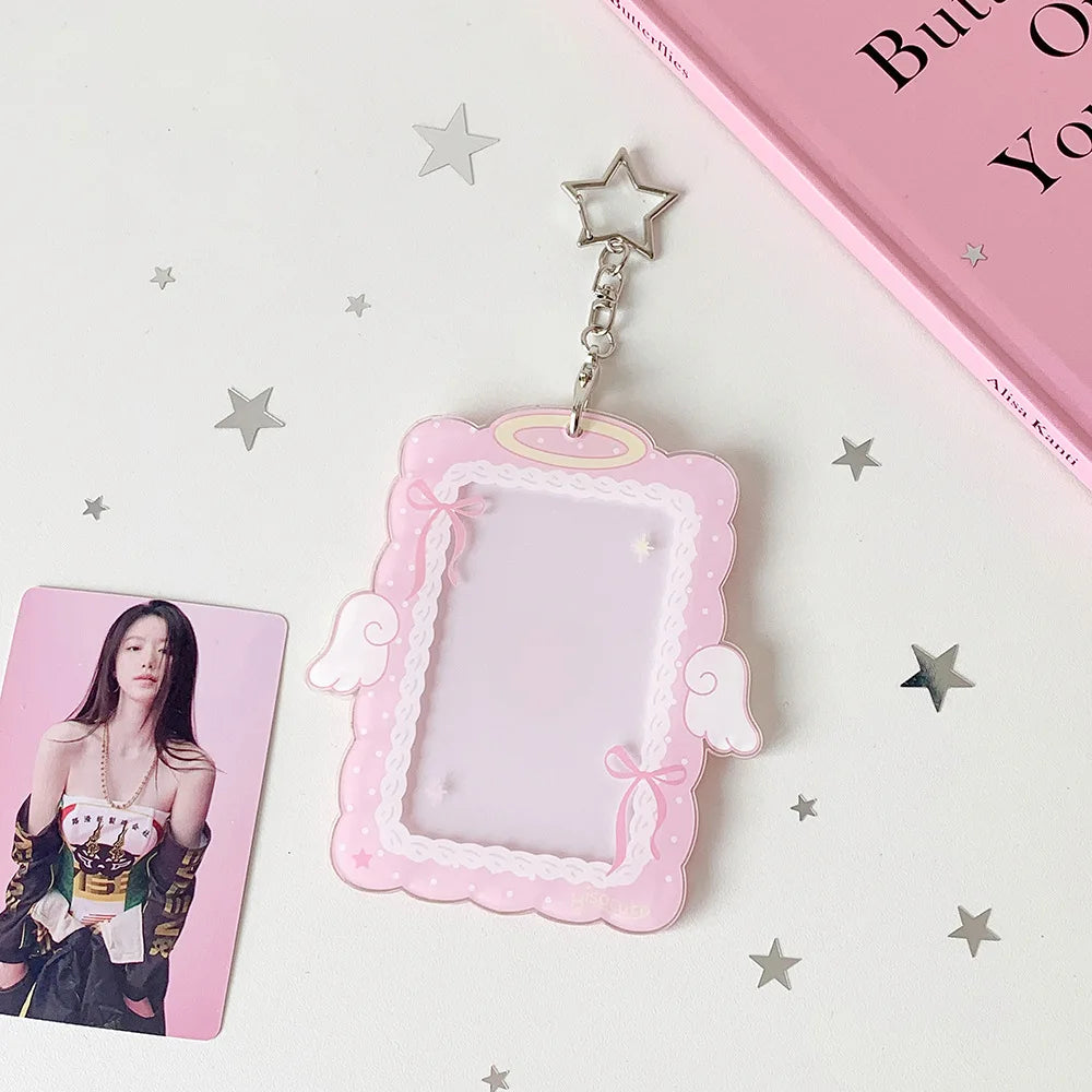 A pink angel wings photocard holder with a clear display case and a star charm on a white background.
