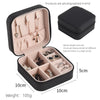 A black compact leather jewelry travel box shown open with multiple compartments for storing necklaces and earrings.