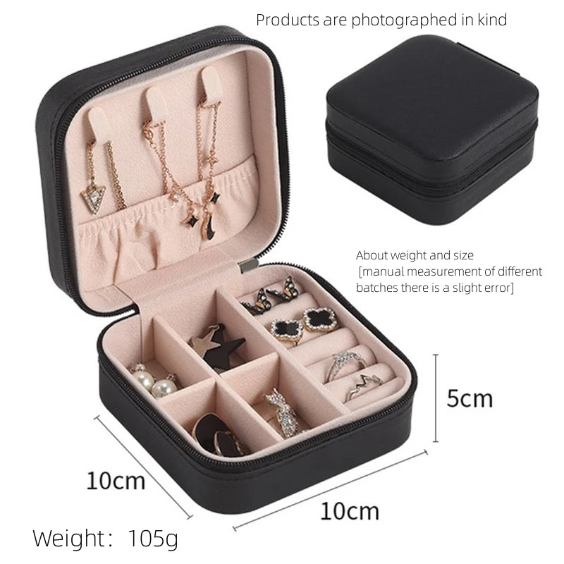 A black compact leather jewelry travel box shown open with multiple compartments for storing necklaces and earrings.