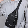 A black sports nostalgic cool stule shoulder bag worn by a person in a gray jacket.